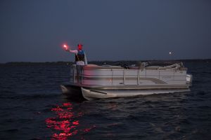 Using a handheld flare at dusk aboard a boat 16-21 feet.