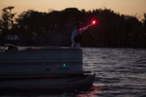 Using a handheld flare at dusk aboard a boat 16-21 feet.