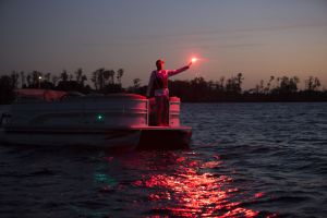 Using a handheld flare at dusk aboard a boat 16-21 feet.