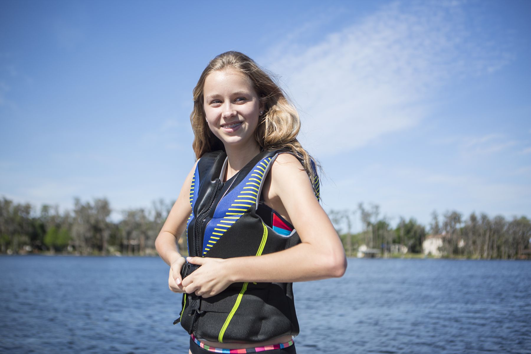 A girl zipping a life jacket for a day on the water.