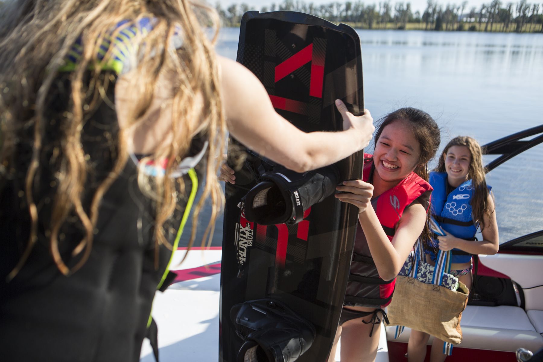 Kids unloading the boat after a day having fun on the water in properly fitting life jackets.