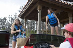 Kids loading the boat for a fun afternoon on the water in properly fitting life jackets.